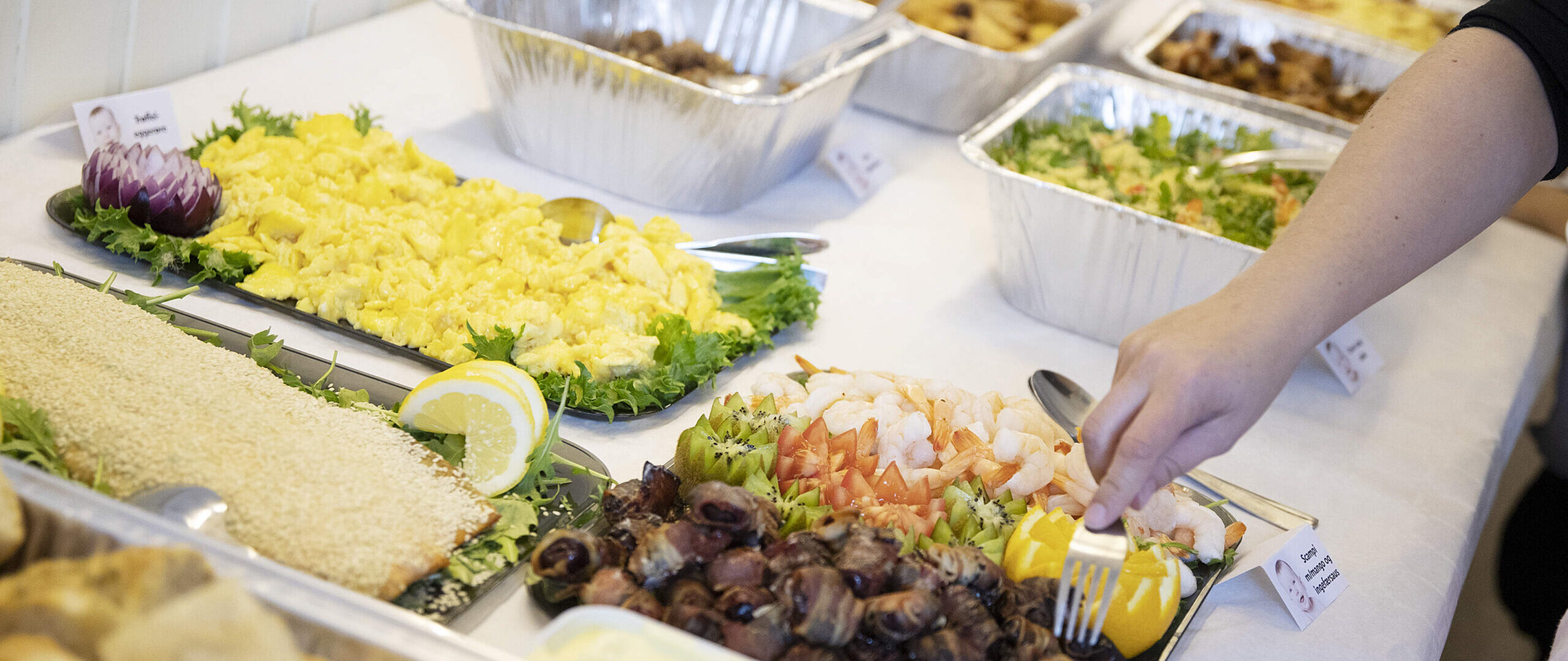 Koldtbord med en hånd som forskyner seg av maten